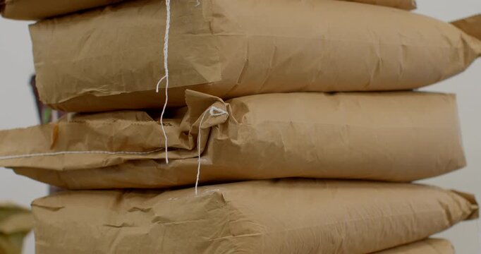 close-up motion of stacked kraft paper packages bound with twine, string position shifts slightly as paper compresses and creases between layers in tight view