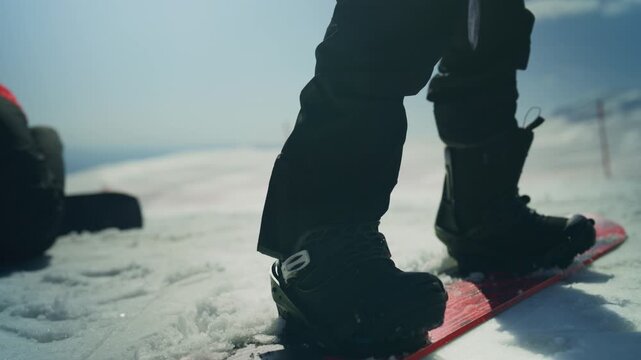 A person on a snowboard stands ready on a snowy mountain slope. Friends are enjoying the winter landscape and outdoor adventure time.