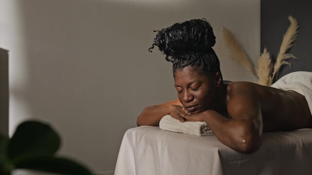 African American woman resting with closed eyes during beauty wellness body treatment. Footage suitable for luxury spa marketing, self-care advertising, and holistic healthcare promotions