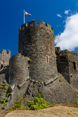 Low angle view of ruined medieval castle fortification showing stone masonry, defensive battlements and Welsh national flag on flagpole © whitcomberd