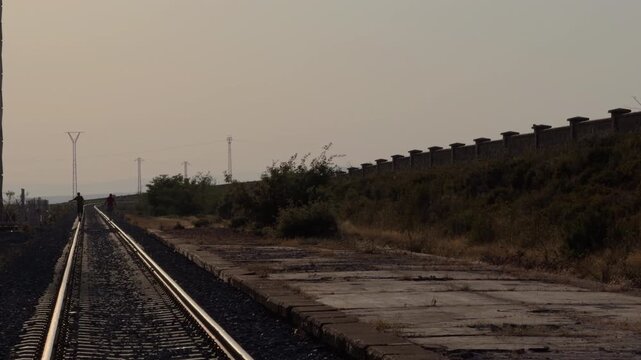 Couple Walking Along Railway Tracks Toward a Veiled Horizon
