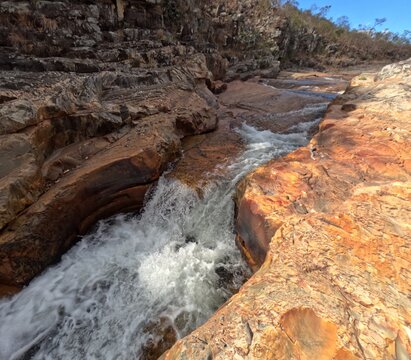 Roaring cascade in an orange rock channel, Chapada dos Veadeiros
