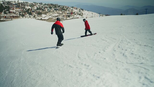 Two snowboarders descend a pristine snow-covered mountain slope. This scene captures the thrill of winter sports in a scenic alpine resort.