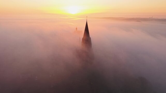 Aerial view of church spire above fog in Kessel, Netherlands.
