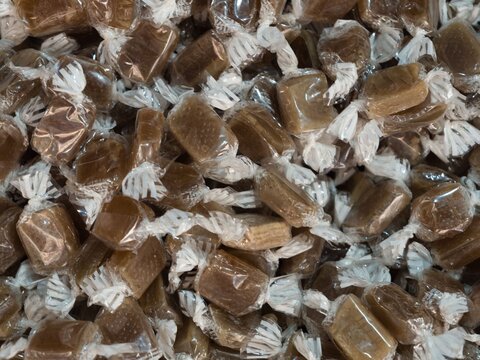 Brown candies wrapped in clear plastic displayed in a close view at a candy shop
