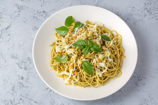 Delicious pasta with pesto sauce, basil and cutlery on white background