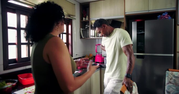 Couple arguing in kitchen, husband showing frustration while wife expresses anger, tense discussion highlighting relationship conflict and emotional strain at home