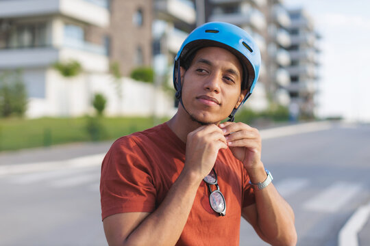 Man adjusts safety helmet while preparing to ride a bicycle in the city