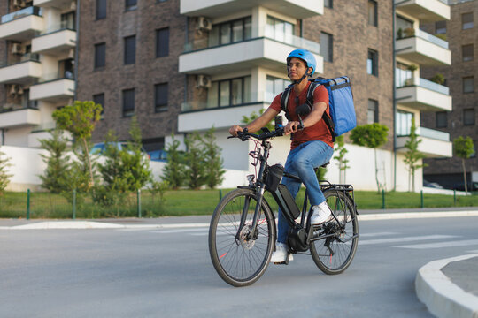 Courier rides electric bicycle and delivers food in urban setting