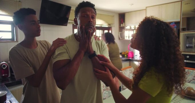 Father overwhelmed as teenage son and daughter surround him, both demanding attention and solutions, family tension highlighting parenting challenges in a busy kitchen