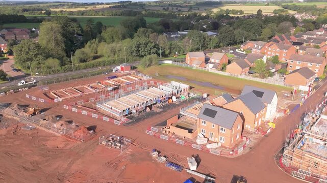 A rising aerial movement of a new phase of a modern housing estate with buildings at various stages of completion