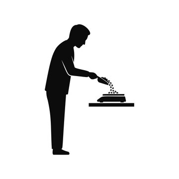 A man carefully weighing roasted coffee beans using a small scoop and a digital scale