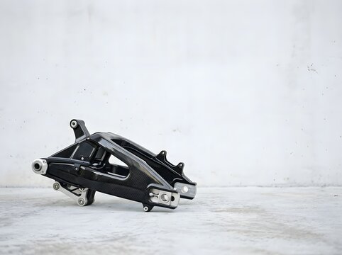 High-performance carbon fiber motorcycle swingarm component for a superbike, featuring intricate weave pattern and precision machined metal mounts on a white background.