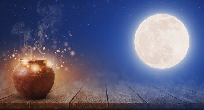 Magic potion pot on a wooden table with smoke and sparkles under a bright full moon at night.