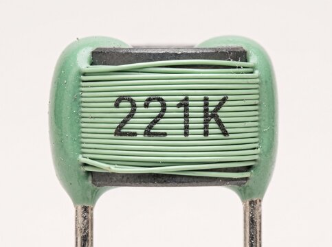 Close up view of green wire wound axial lead inductor with numeric value marking on body.