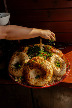 Close-up of a man's hand Sprinkling fresh herbs on a tandoor bread and pilaf rice platter