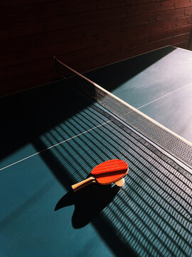 Close-up of a Table tennis bat and ball on a ping pong table with dramatic shadows