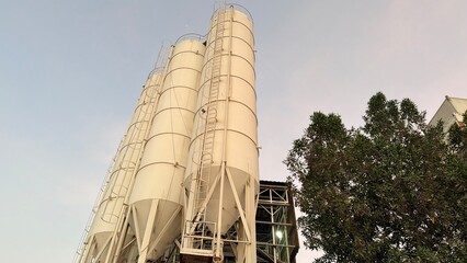 Four large vertical cylindrical cement silos used for bulk material storage at an industrial concrete batching plant. © Mekarim1983