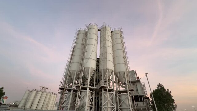 Four large vertical cylindrical cement silos used for bulk material storage at an industrial concrete batching plant.