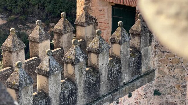 High angle detail shot of the weathered stone battlements and intricate finials of the Alcazar fortress in Segovia, Spain on a bright sunny winter day.