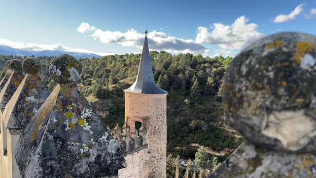 Depth of field shot showcasing the stone crenellations and iconic pointed turret of the Alcazar of Segovia castle under a clear sunny sky in Segovia, Spain.