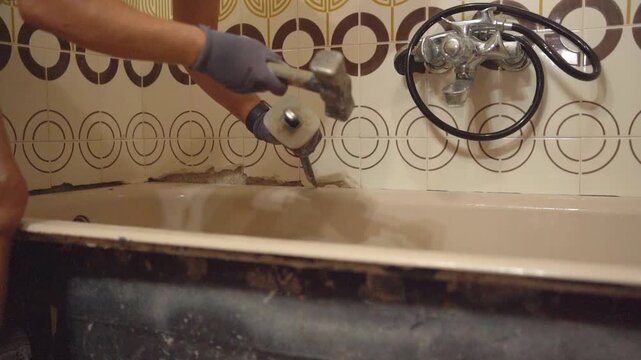 close up of hands doing renovation work at home, hitting bathroom tiles with hammer