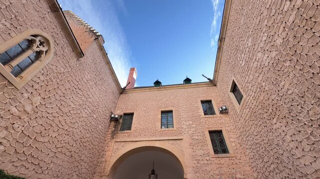 Low angle upward shot revealing the intricate stone texture and arched architecture of the historic Alcazar castle facade under a clear blue sky in Segovia, Spain.