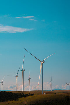 Wind farm turbines generating clean energy on a rural landscape under a clear blue sky, illustrating renewable power