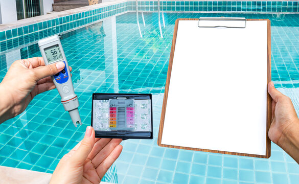 Swimming pool water testing test kit with blank report paper on wooden clipboard over clear pool water background, quality water tester technology