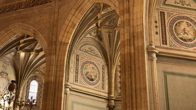Slow tracking shot revealing the ornate Gothic architecture and intricate religious frescoed walls inside the historic Segovia Cathedral in Segovia, Spain.