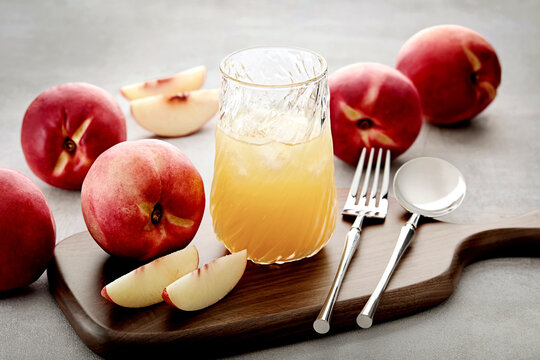 Close-up of a glass of Chilled Peach Juice with Fresh Peaches on a wooden chopping board