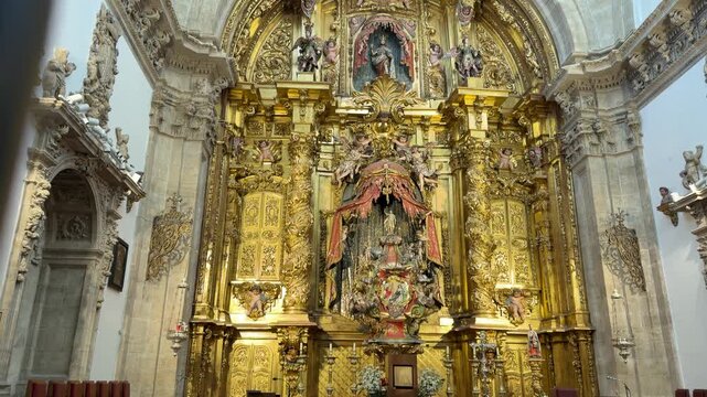 Slow zoom shot exploring the intricate golden altarpiece with Baroque statues and ornate carvings inside the historic Segovia Cathedral in Segovia, Spain.