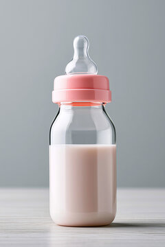 Glass baby feeding bottle filled with fresh milk and topped with a pink cap on a table.