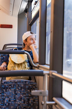 Portrait of a Teenage boy wearing a baseball cap sitting on a bus looking out of the window