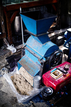A blue industrial denim recycling shredder machine powered by a small diesel engine in a factory setting.