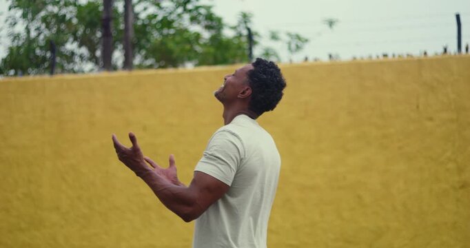 Man of African descent looking upward with open hands, expressing hope, gratitude, and faith, a serene moment of prayer and devotion, connecting deeply with spirituality