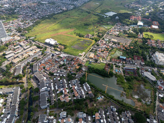 Obraz premium Aerial View of Suburban Residential District Bordering Green Fields and Small Lakes