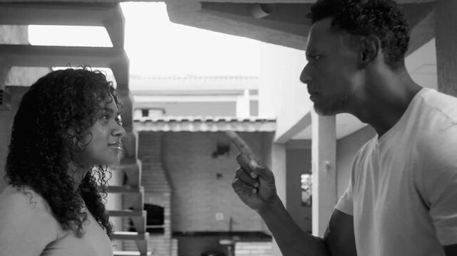 Man pointing finger in monochromatic scene with serious expression, teenage daughter reacting emotionally with hand on chest, tense moment conveying conflict, confrontation, or discussion