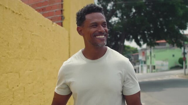 Man walking forward with relaxed expression, smiling as he looks to the side, exuding happiness, contentment, and positivity in casual outdoor moment