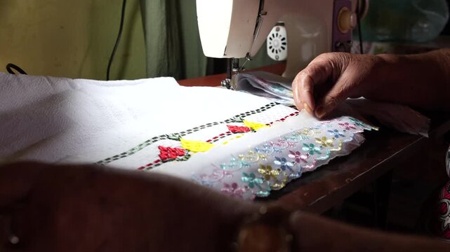 Pessoa idosa costurando tecido em m&aacute;quina de costura dom&eacute;stica, trabalho artesanal tradicional feito em casa