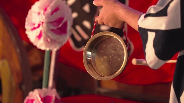 祭りの山車に参加する鐘を叩く男性