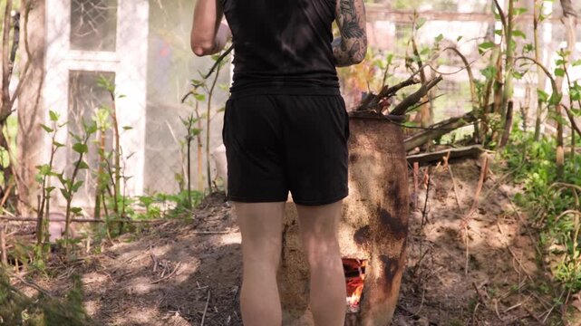 Man burns branches in backyard while cleaning up yard in late spring afternoon