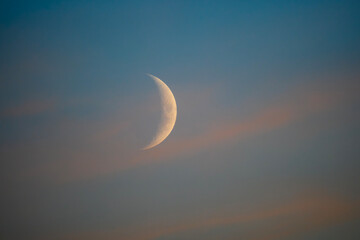 Beautiful close up of a sharp crescent moon in a colorful sunset sky background © underwaterstas