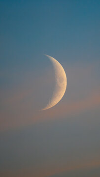 Beautiful vertical view of a sharp crescent moon in a colorful sunset sky background