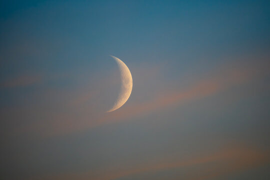 Beautiful close up of a sharp crescent moon in a colorful sunset sky background