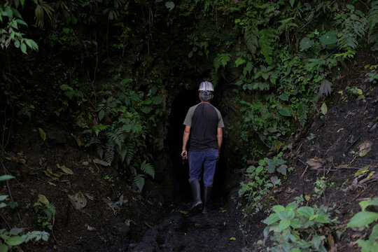 Miner entering dark jungle cave for exploration