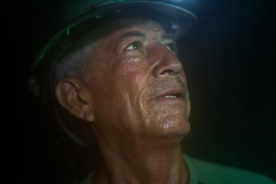Miner worker with headlamp looking up in dark underground