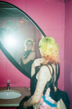 Woman fixing hair in pink bathroom mirror