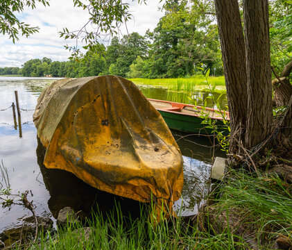 ein kleines, am Ufer liegendes Boot, das vollst&auml;ndig mit einer alten, verwitterten gelben Plane abgedeckt ist, Brandenburg, Deutschland