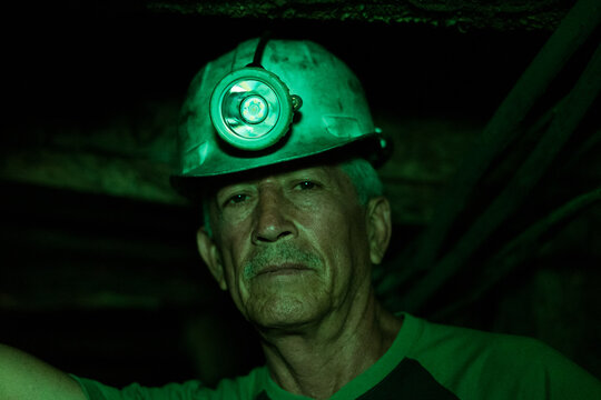 Senior miner wearing hard hat with lamp underground